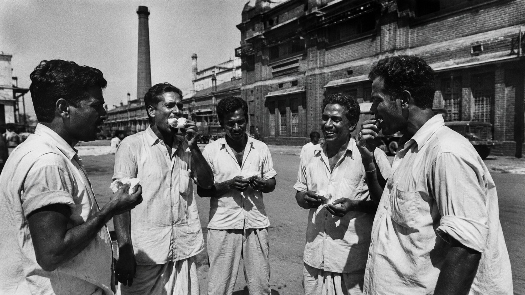 Black and white photograph of Mumbai textile mill workers during lunch break in the 1960s